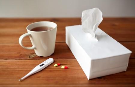 Image of a cup of coffee, thermometer and kleenex on a table