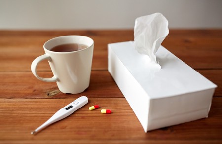 Tissue, cup of tea, and thermometer